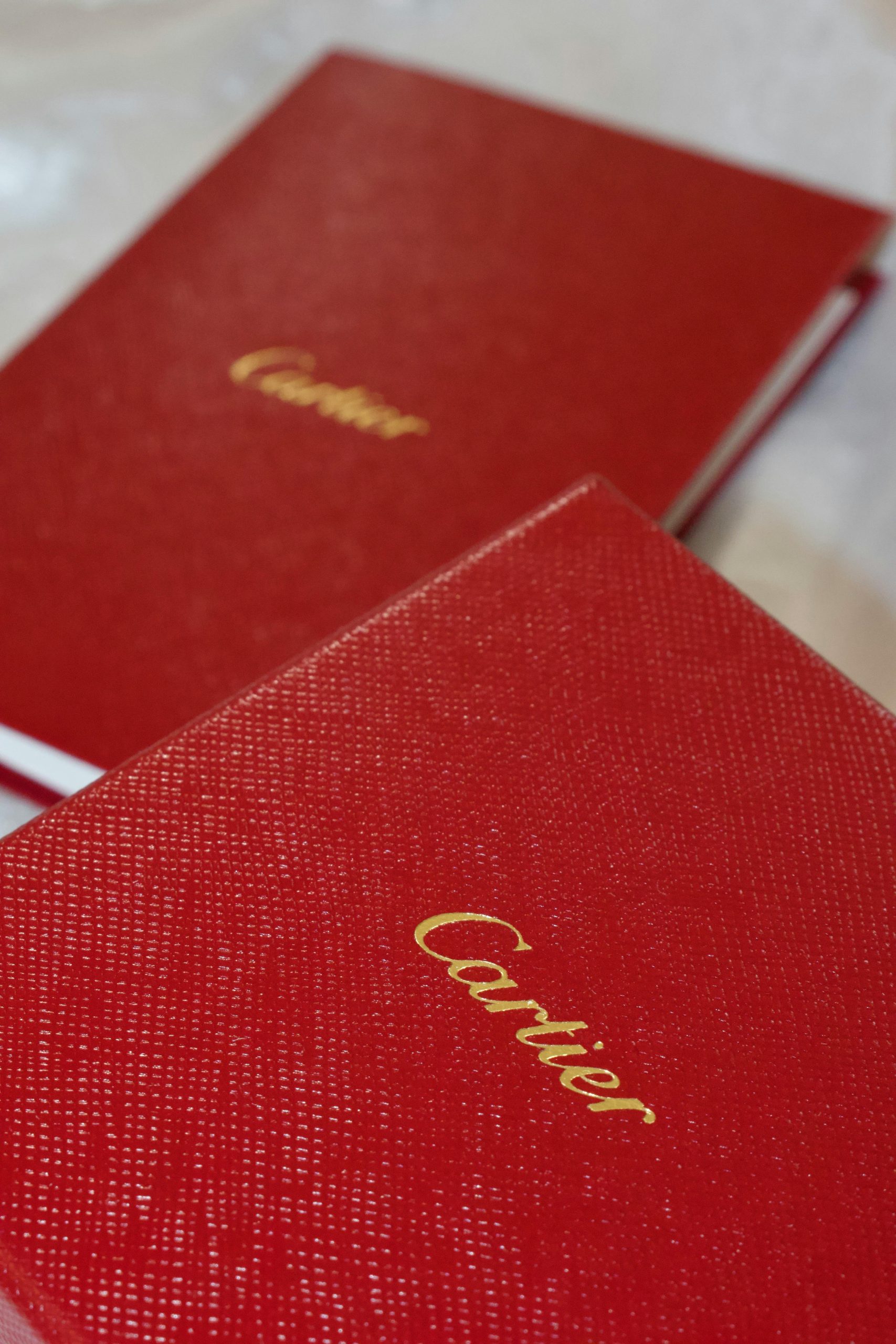 Close-up of luxury red notebooks featuring gold embossed lettering, emphasizing elegance.