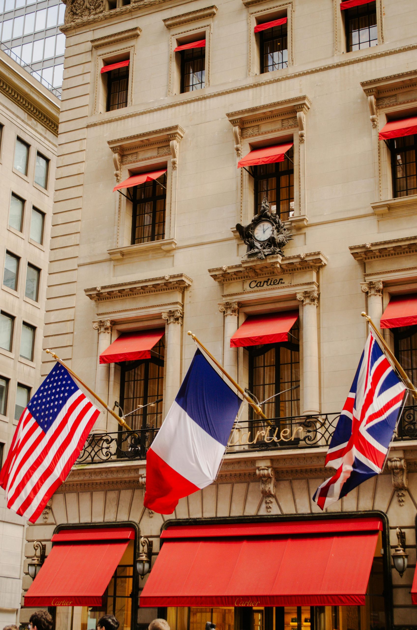 Cartier building adorned with American, French, and UK flags in vibrant city setting.